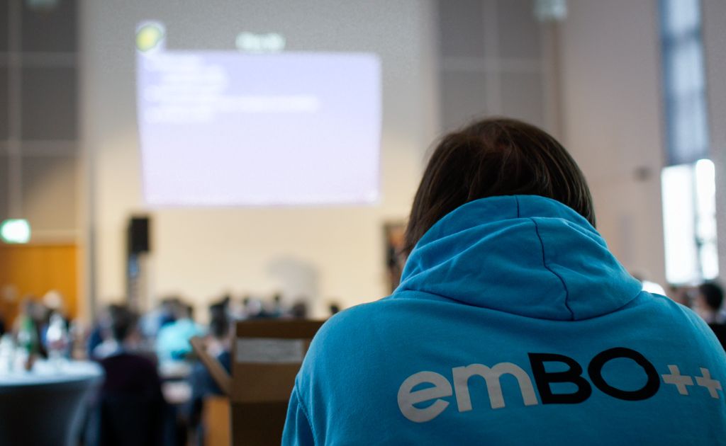 Attendee in an emBO++ hoodie watching a talk